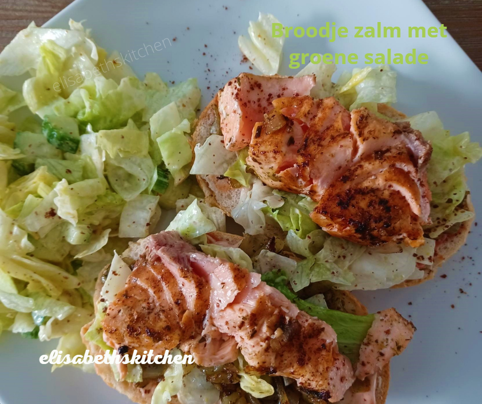 Open zalmsandwiches met groene salade op een wit bord.