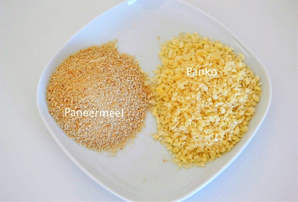 Twee soorten paneermeel op een wit bord: lichtbruin paneermeel en luchtig, geel panko-paneermeel.