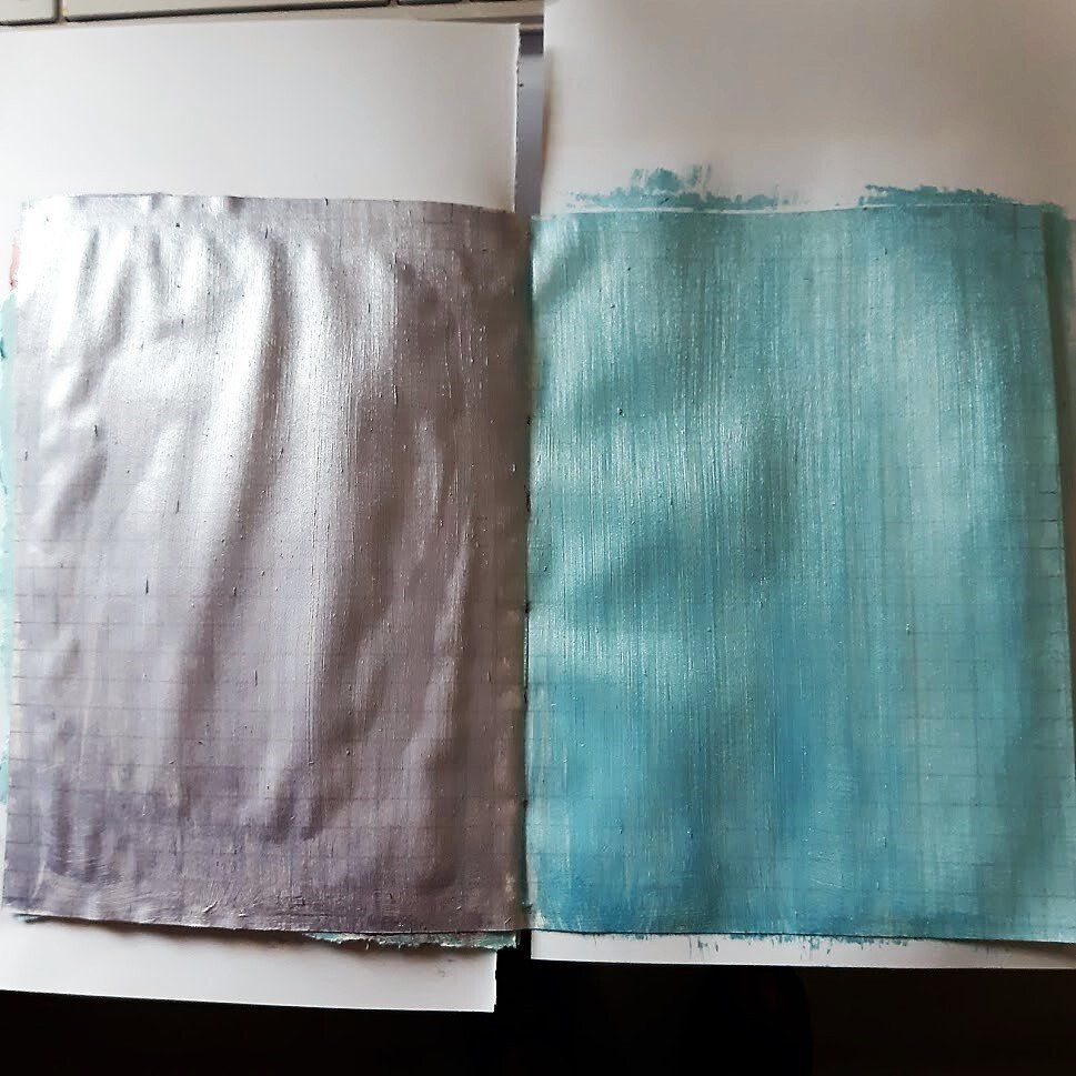 Twee rechthoeken stof, een zilverkleurige en een turquoise, geschilderd op ruitjespapier.