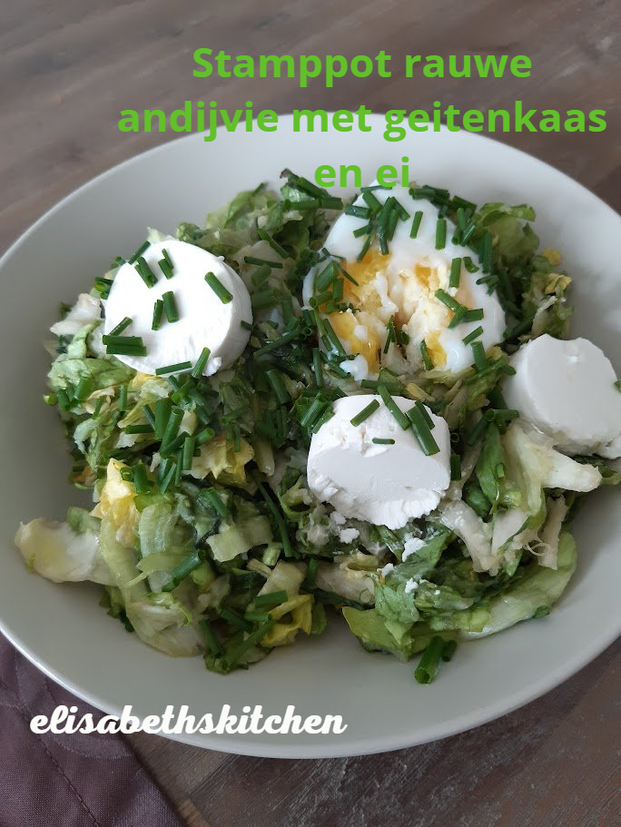 Stampot met rauwe witlof, geitenkaas en ei op een wit bord, gegarneerd met bieslook.