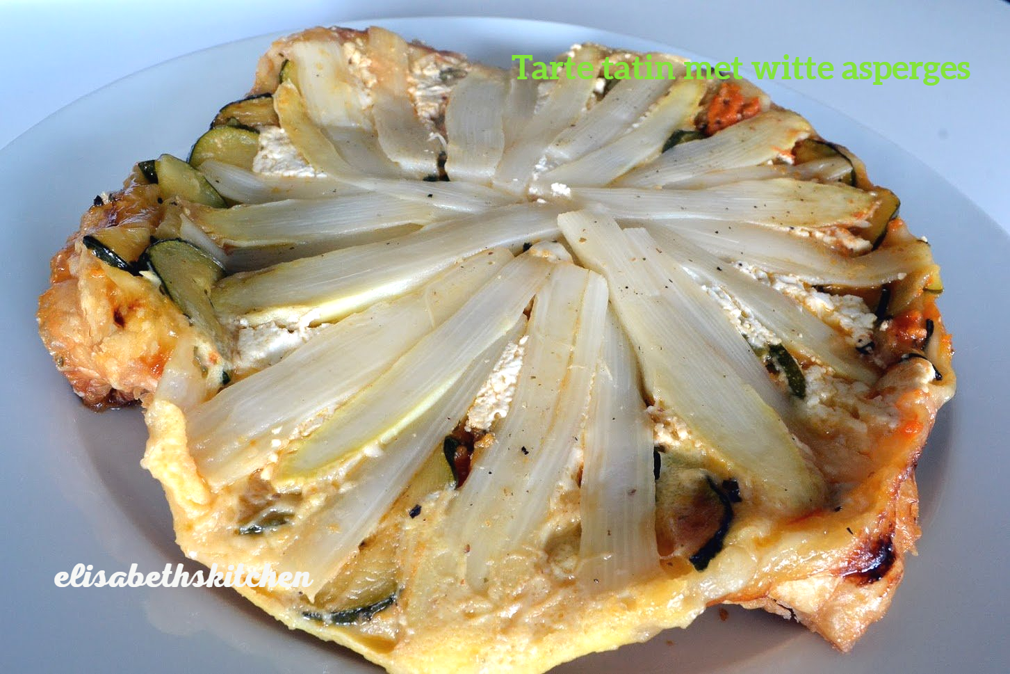 Taart met witte asperges, courgette en kaas, gebakken op een bord.
