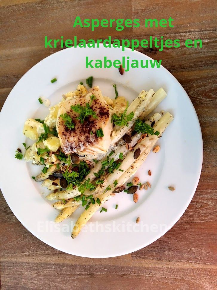 Witte asperges, kabeljauw en aardappelen op een bord, gegarneerd met peterselie en zaden.