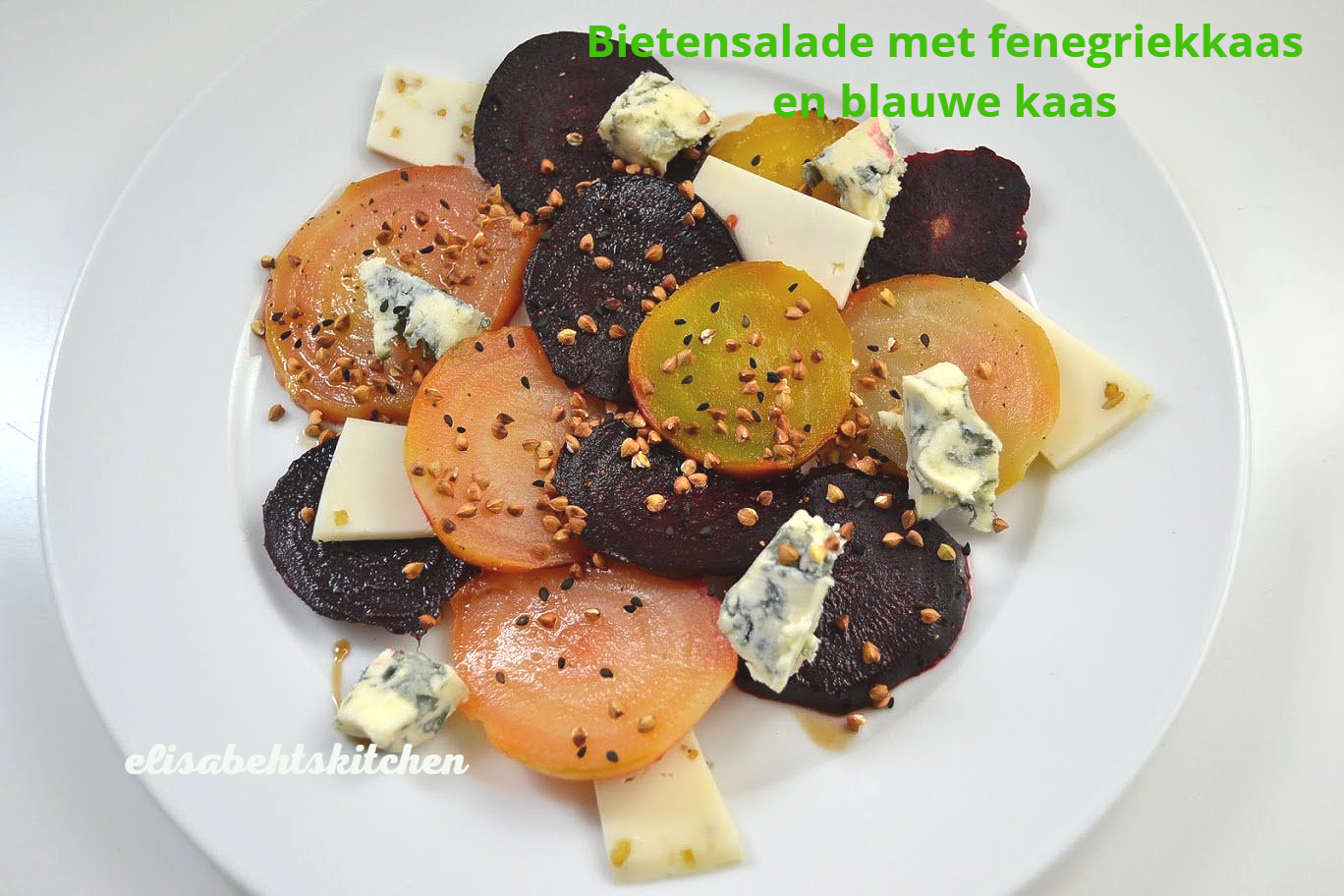 Bietensalade met plakjes biet, kaas en blauwe kaas op een wit bord.