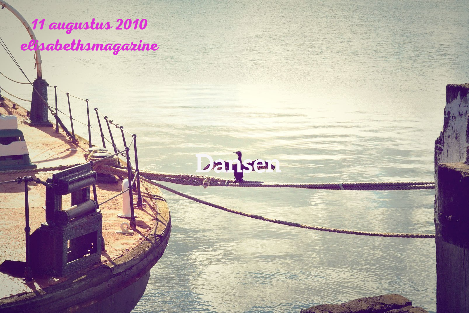 Oud schip aangemeerd aan een pier, met water en een vergezicht in de verte. De tekst 