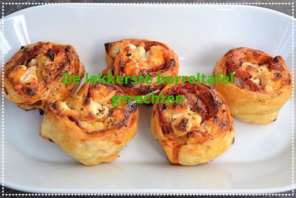 Vijf spiraalvormige gebakjes met kaas en een donkere topping op een wit bord.