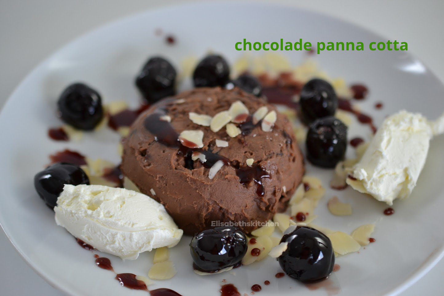 Verderop de pagina staat het recept Chocolade panna cotta dessert met kersen, slagroom en amandelschaafsel op een wit bord.