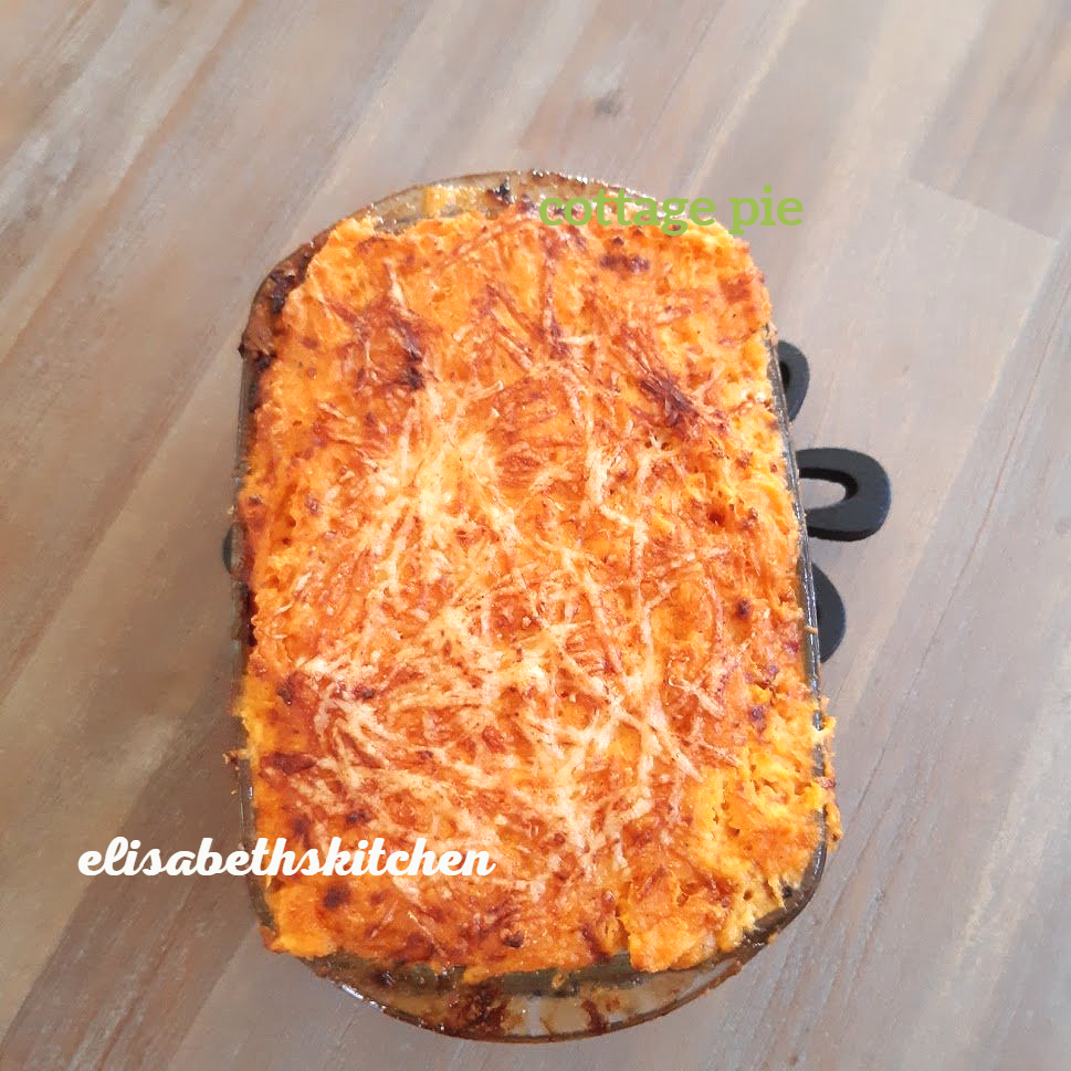 Een ovenschotel in een rechthoekige bakvorm, bedekt met een goudbruine laag kaas en wat lijkt op zoete aardappel.