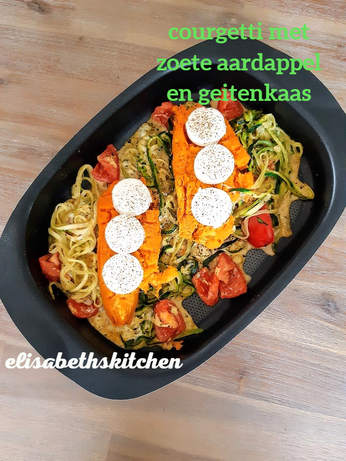 Courgettigerecht met zoete aardappel, geitenkaas en tomaten, in een zwarte pan.