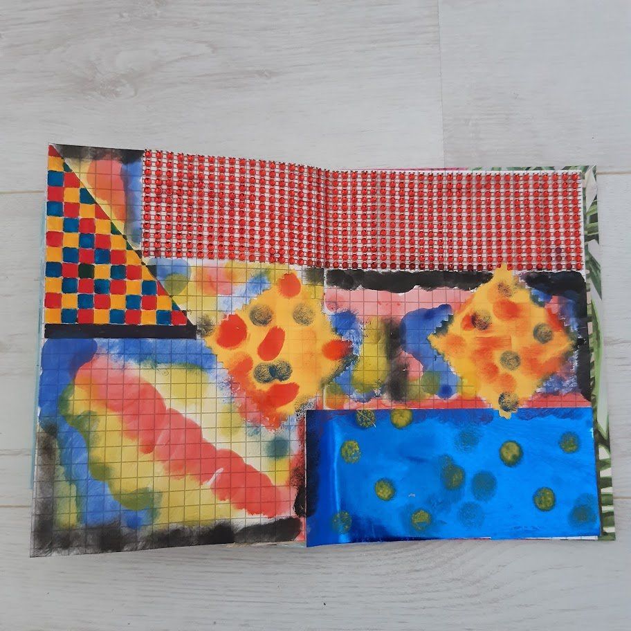 Kleurrijk abstract kunstwerk op een open boek, met een raster, ruiten en gestructureerd papier.