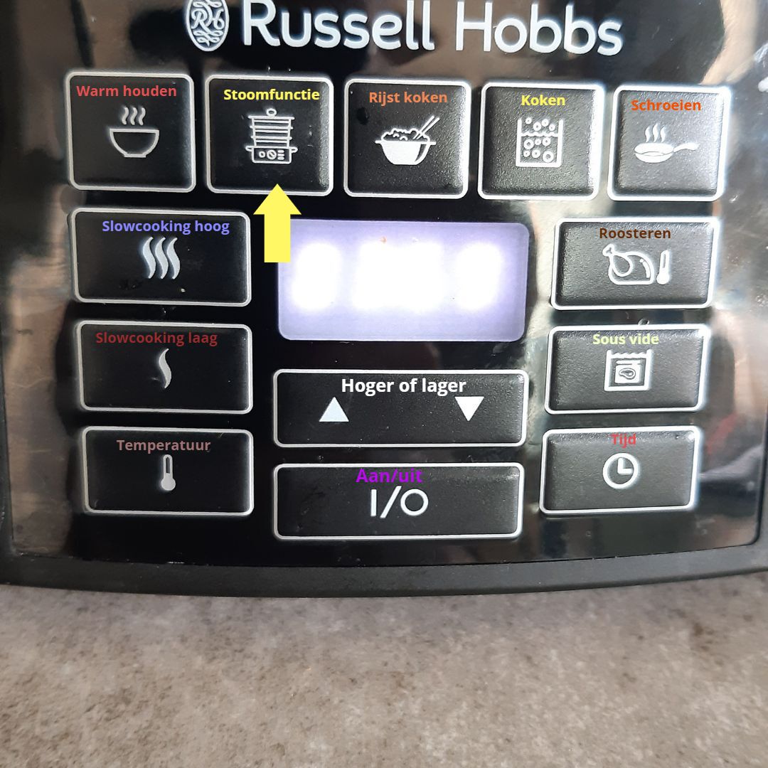 scroll verder voor het recept Bedieningspaneel van een Russell Hobbs-apparaat met knoppen die de kookfuncties aangeven, een oplichtend display en een pijl die naar