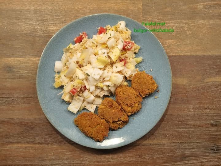 Verderop de pagina staat het recept Blauw bord met salade en vier goudbruine burgers op een houten ondergrond.