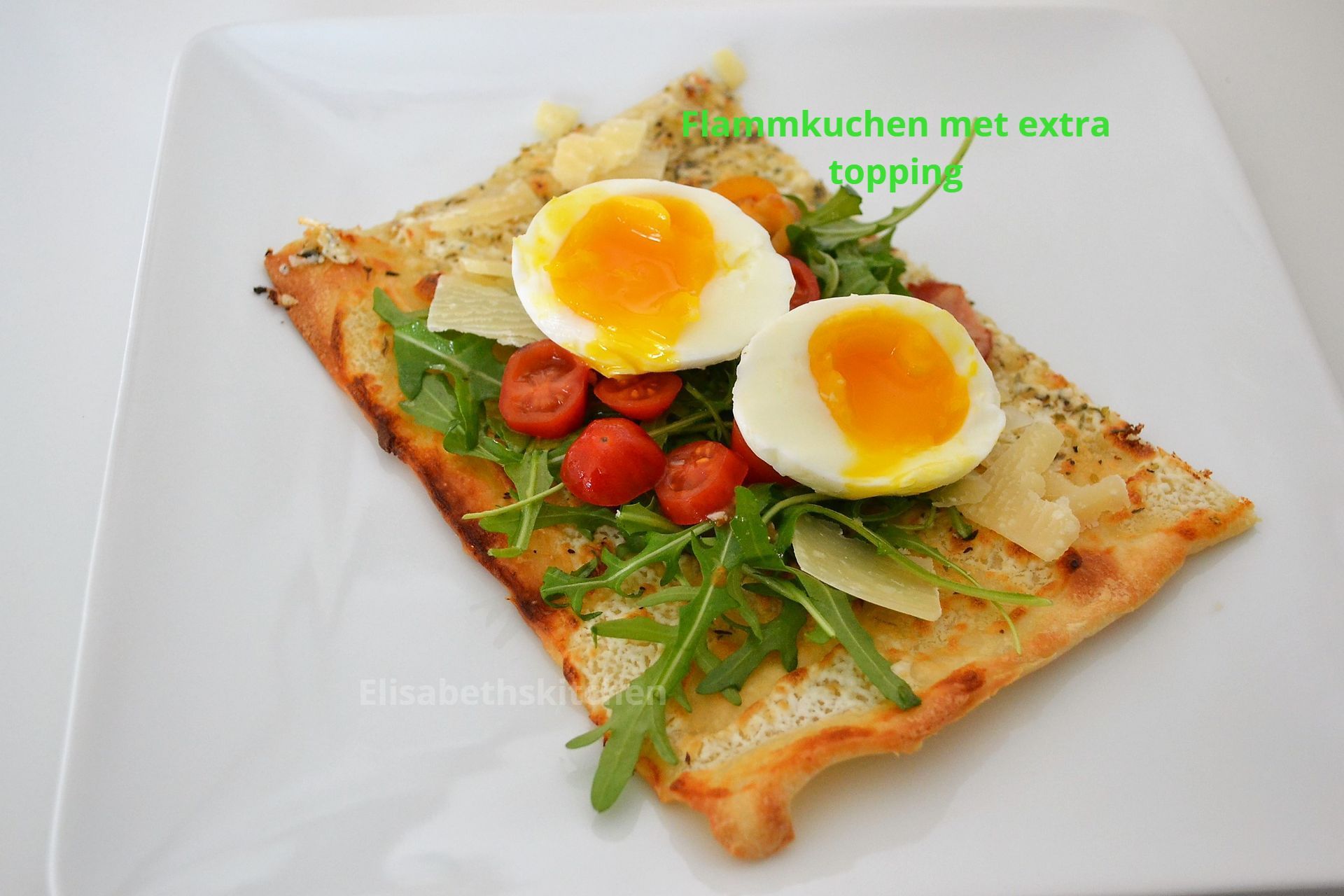 Flammkuchen, gegarneerd met ei, rucola en tomaten, geserveerd op een wit bord.