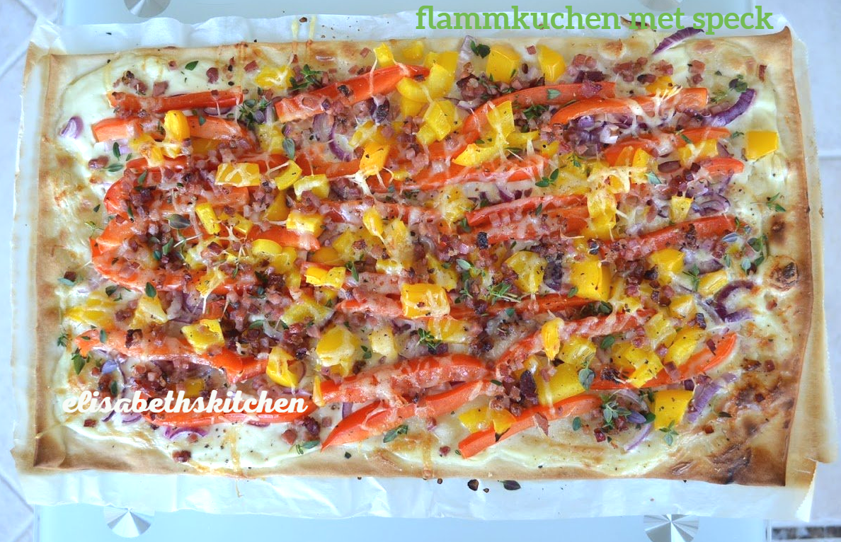 Flammkuchen met toppings: spek, paprika, uien, kruiden en kaas. Gebakken op bakpapier.