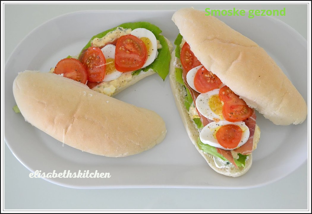 Open sandwiches met tomaat, ei en sla op een wit bord.