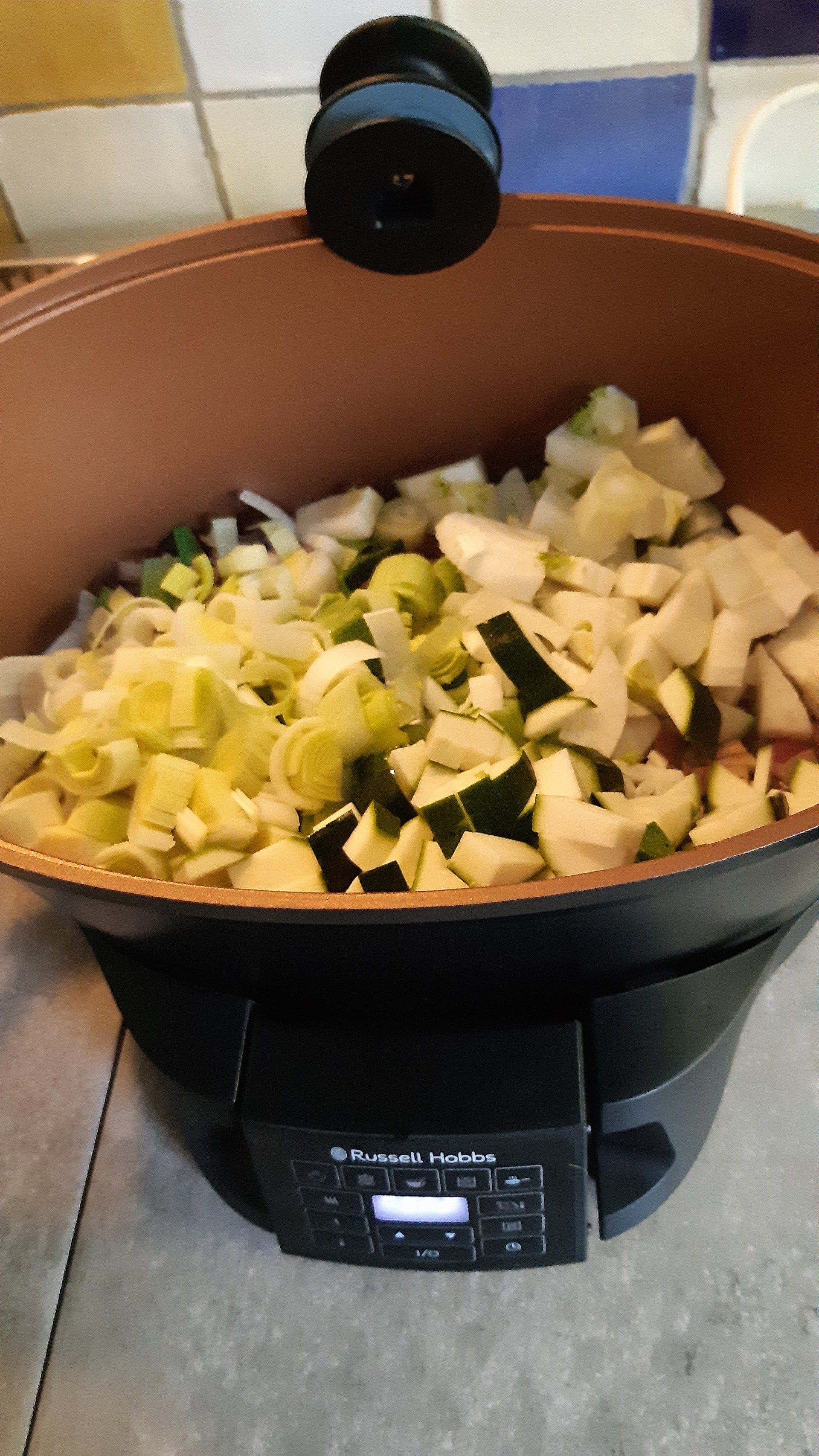 Groenten worden gesneden in een koperkleurige elektrische wok met een digitaal bedieningspaneel.