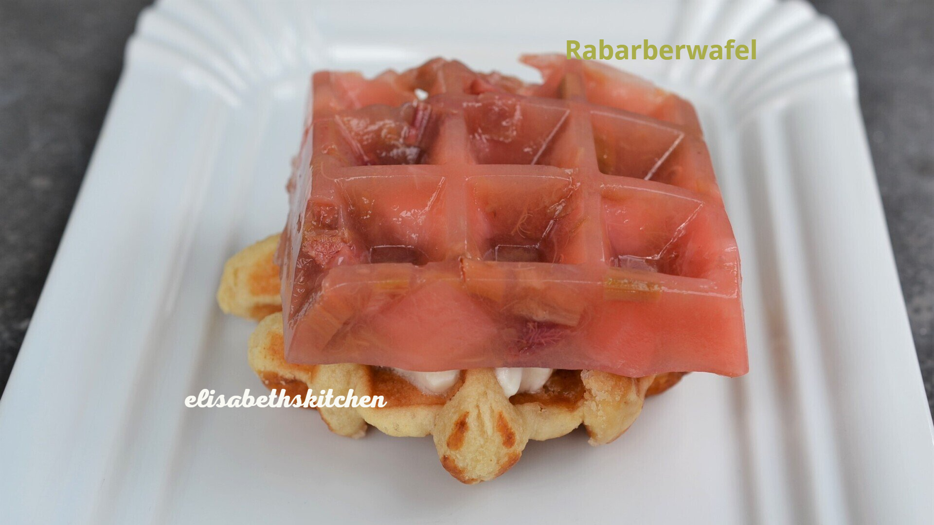 Rabarberwafel met een laagje roze gelatine erbovenop en slagroom. Geserveerd op een wit bord.