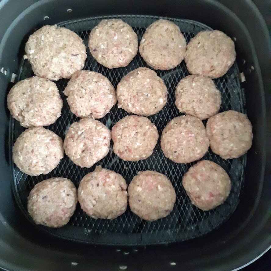 Rauwe gehaktballetjes in een mandje van de airfryer.
