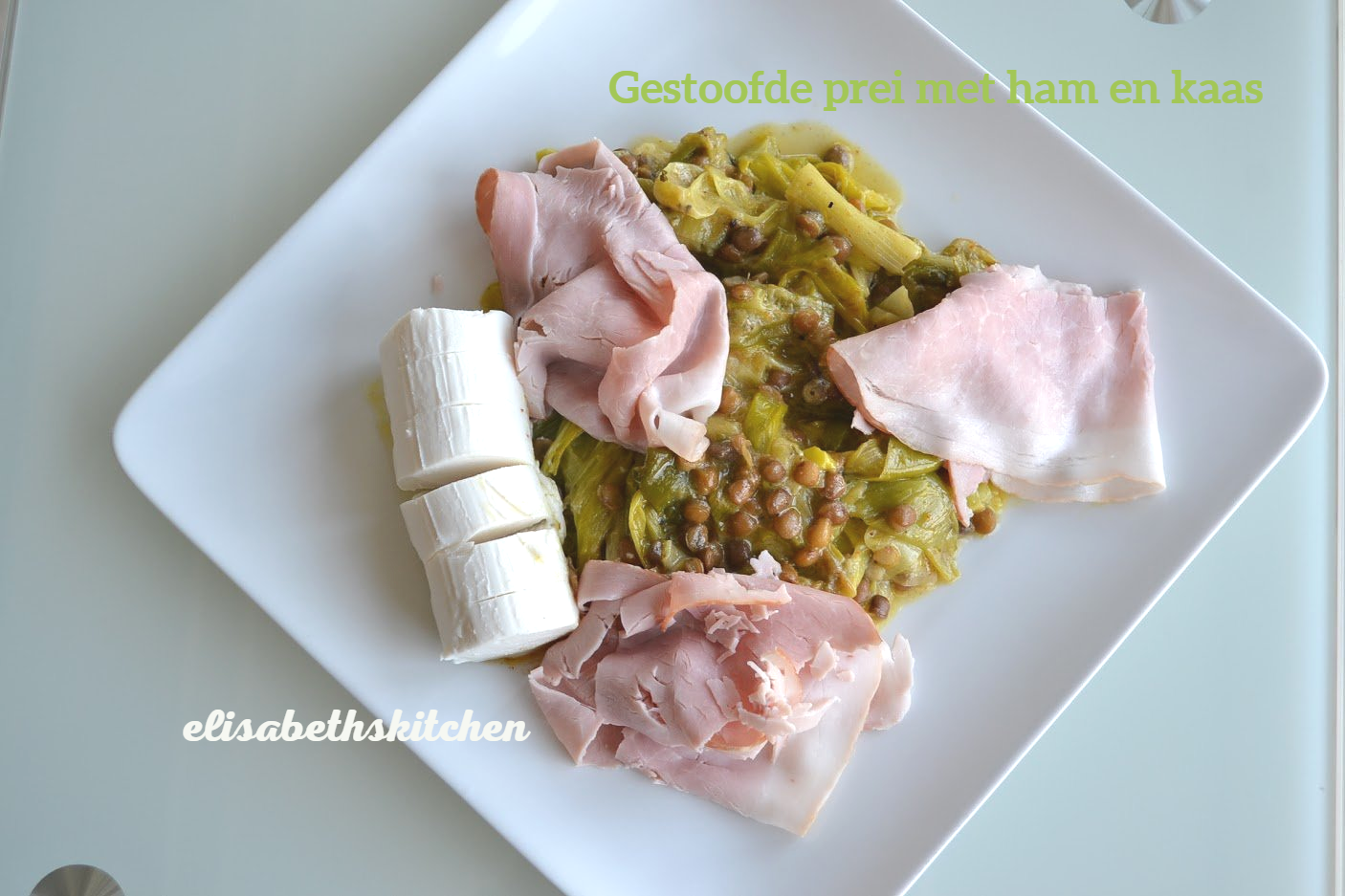 Wit bord met gebakken groenten, plakjes ham en een blok kaas.