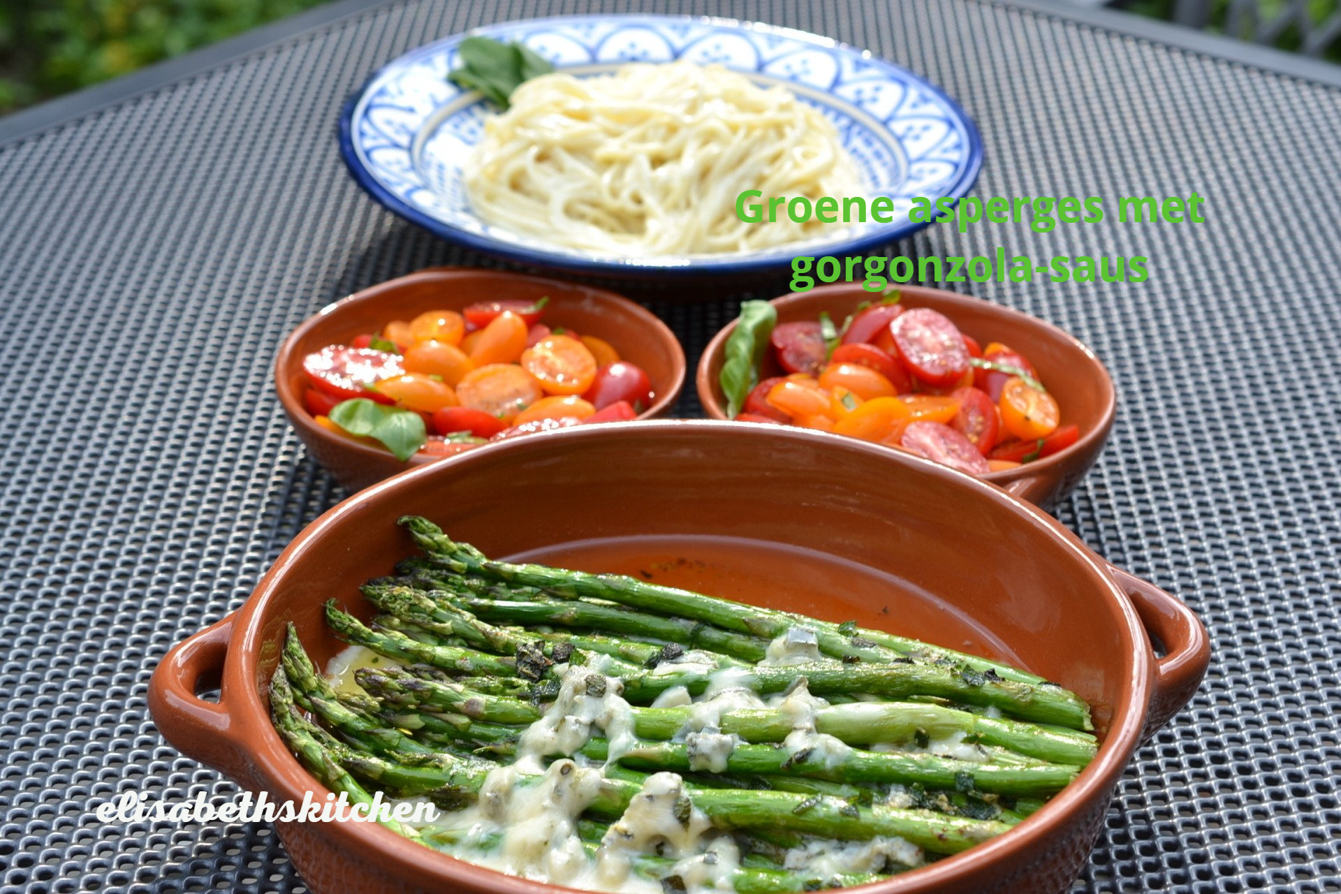 Asperges met saus, pasta en tomaten in schalen op een tafel.