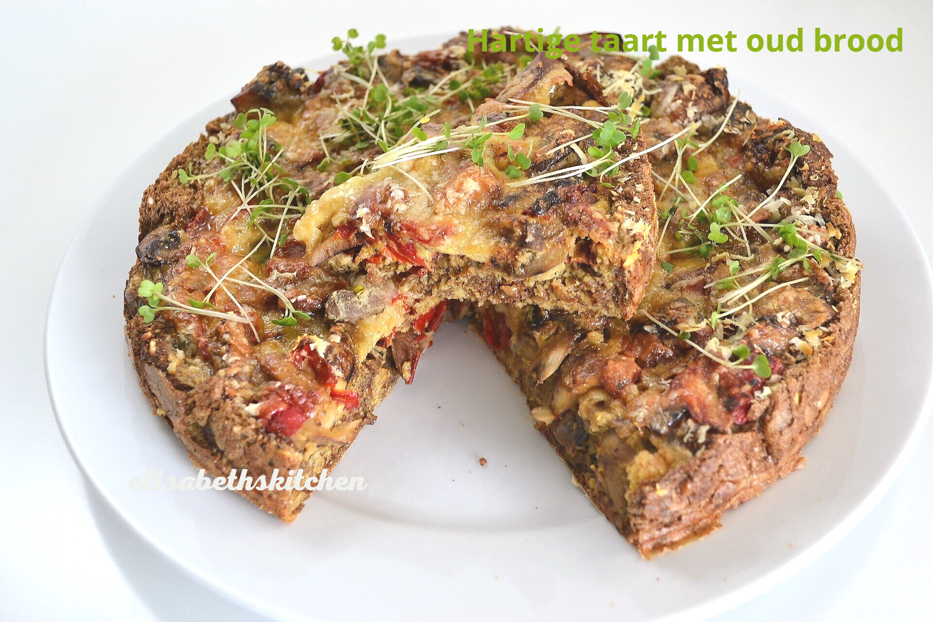 Hartige broodpudding met champignons en rode paprika op een wit bord, gegarneerd met taugé.