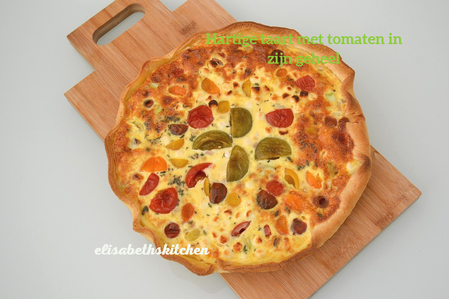Tomatenquiche op een houten plank; kleurrijke cherrytomaatjes verwerkt in de custard.