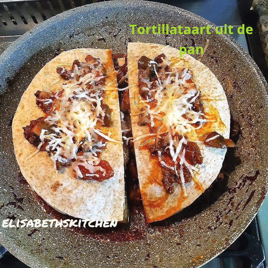 Tortillahelften in een pan met vlees, groenten en kaas.
