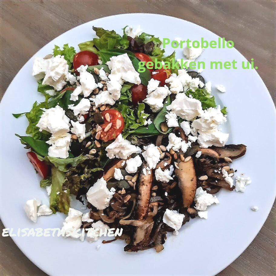 Salade met gebakken portobellochampignons en verkruimelde feta, op een wit bord.