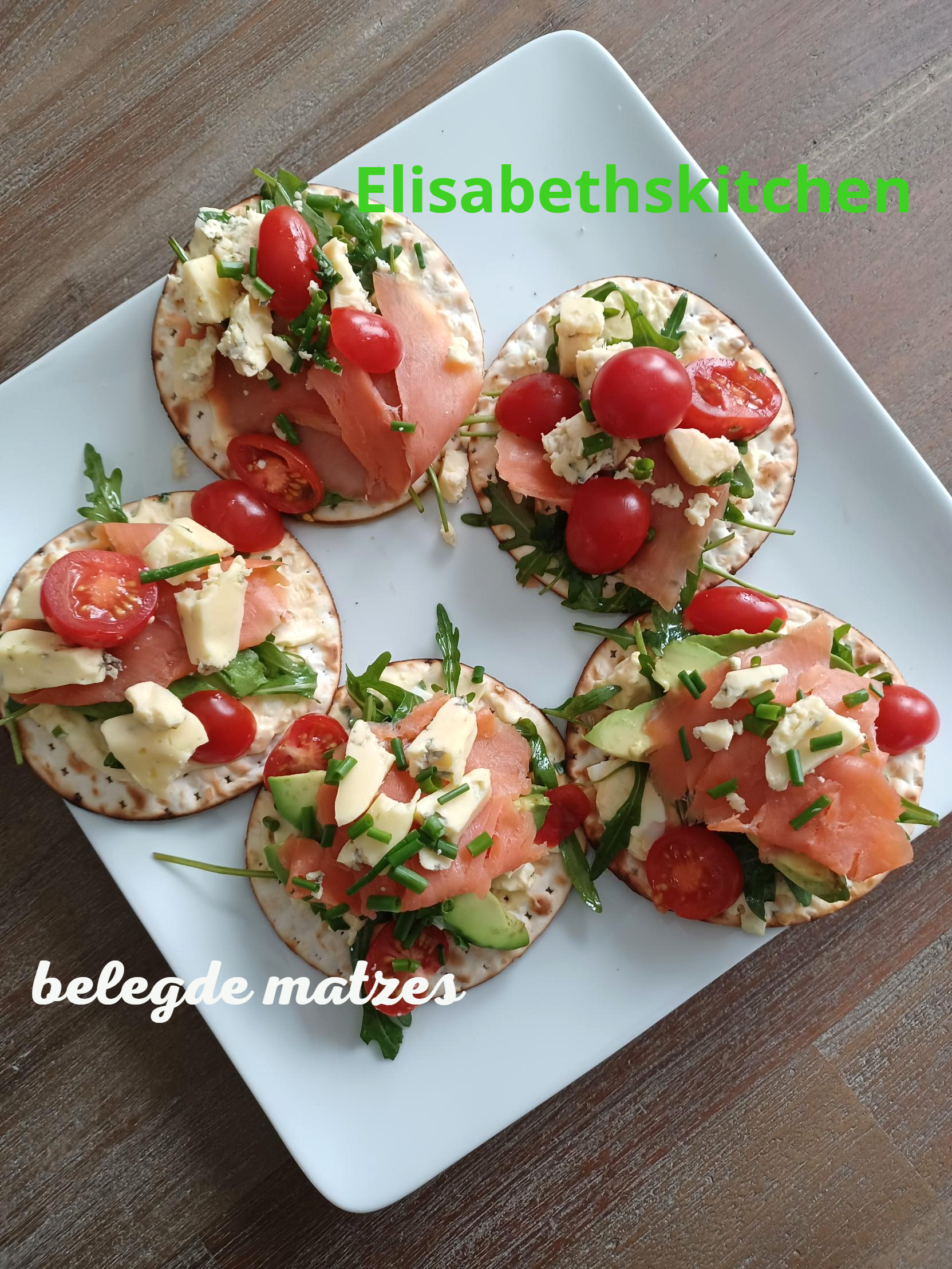 verder op de pagina staat het recept Vijf crackers belegd met gerookte zalm, avocado, kaas, tomaten en rucola op een wit bord.