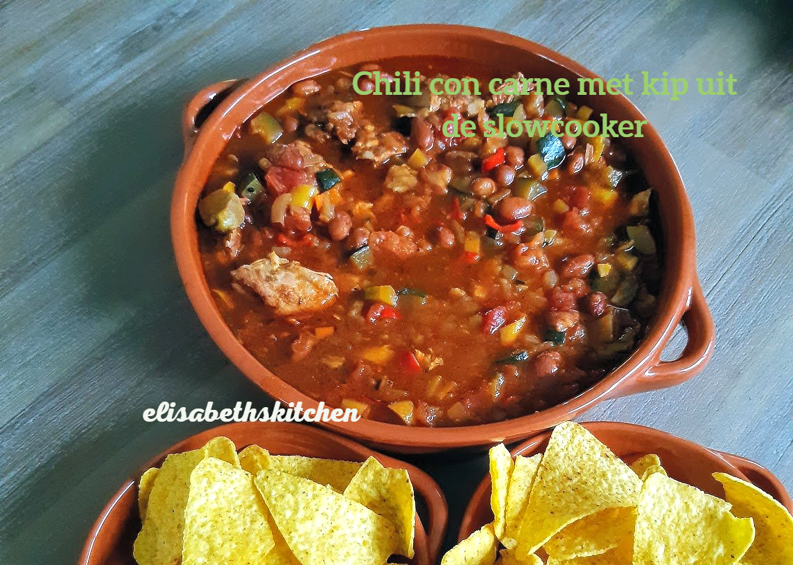 Chili con carne met tortillachips in een bruine kom, op een houten ondergrond.