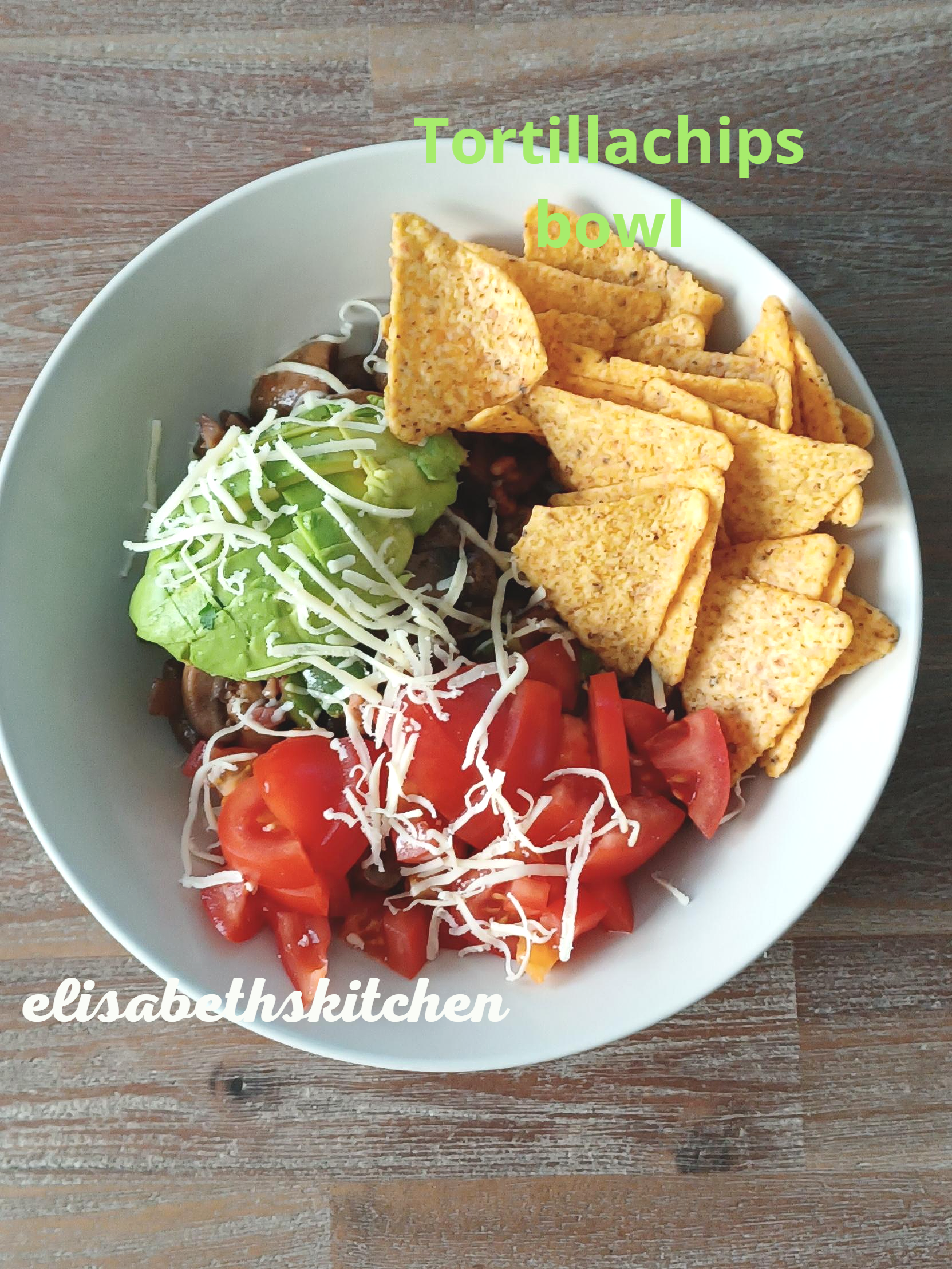 Een kom tortillachips met avocado, tomaten en kaas.
