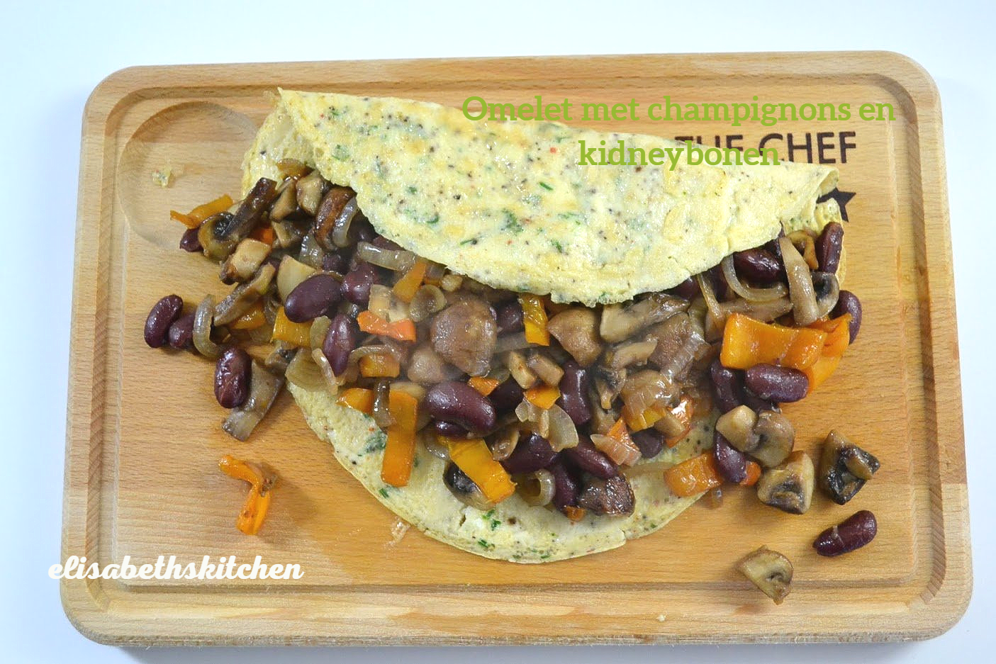 Omelet met champignons en kidneybonen op een houten plank.