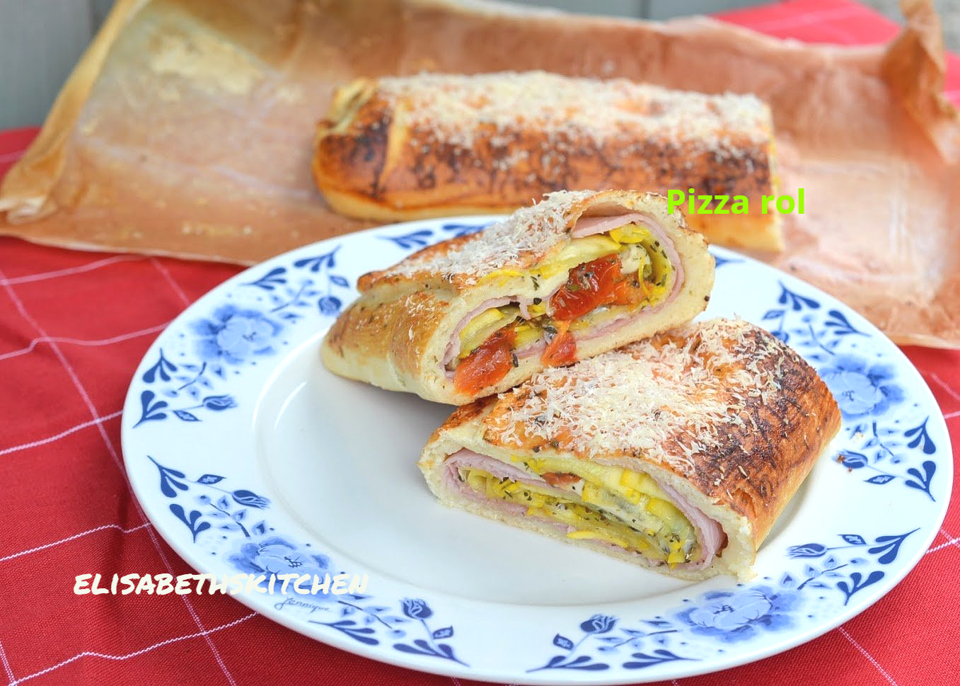 verder op de pagina staat het recept Een opengesneden pizzarol op een bord; laagjes ham, ei, tomaat en kaas.
