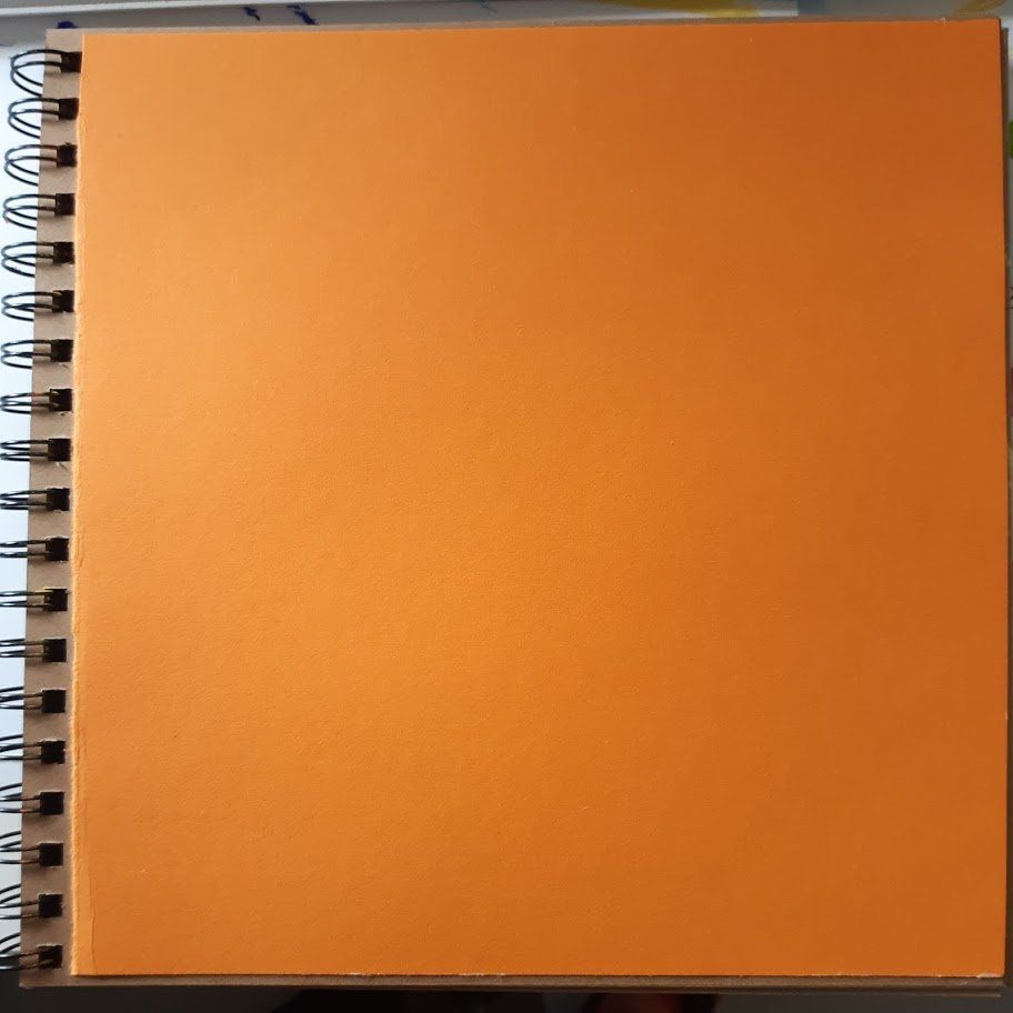 Oranje vierkant schetsboek met spiraalbinding.