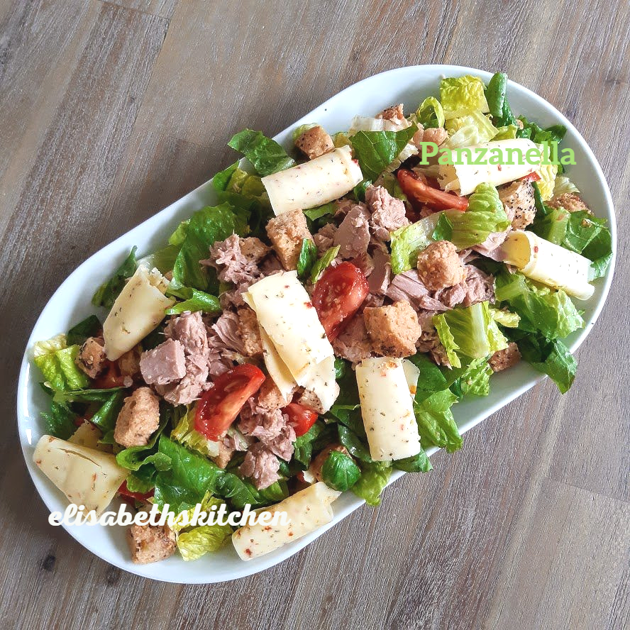 Panzanellasalade met tonijn, tomaten en kaas op een wit ovaal bord.