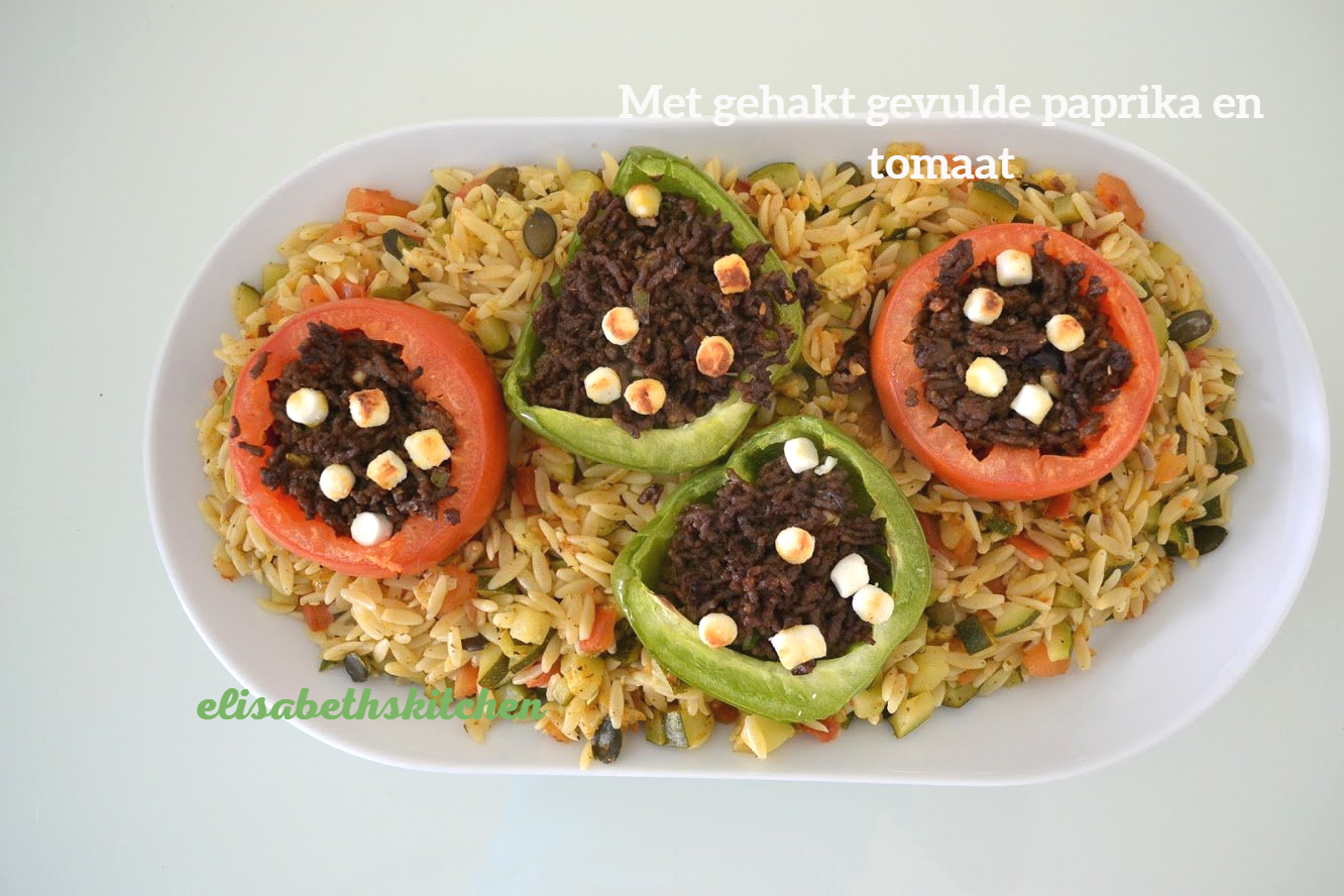 Gevulde paprika en tomaat met rijst. Groene en rode groenten met een vleesvulling, afgetopt met witte kaas.
