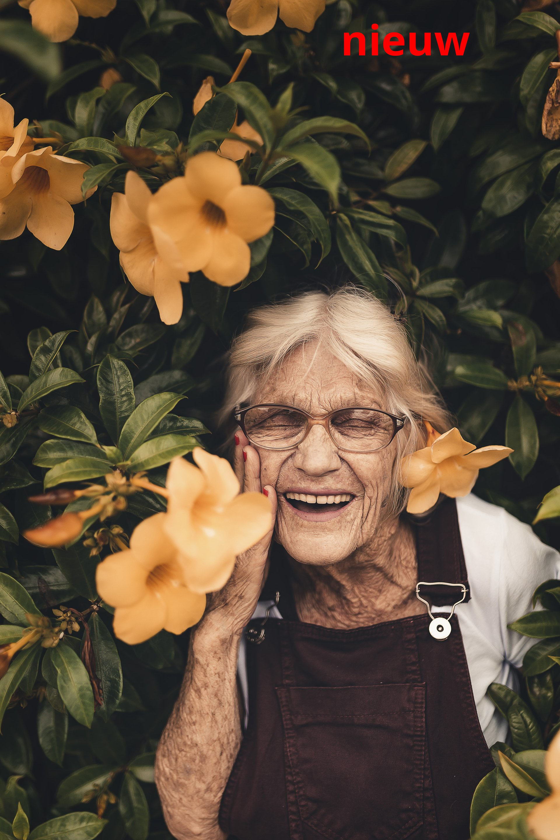 Een oudere persoon lacht tussen gele bloemen. Het woord 