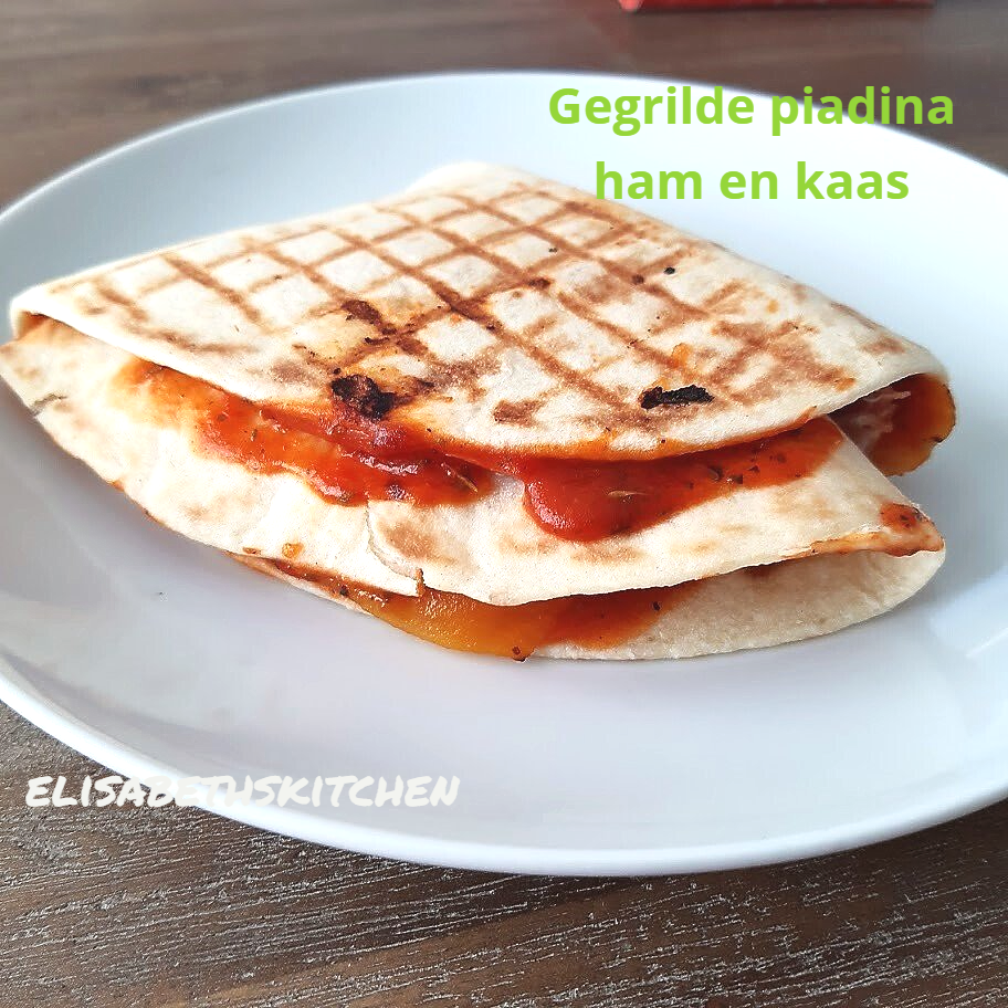 Gegrilde ham- en kaaspiadina op een wit bord, met tomatensaus.