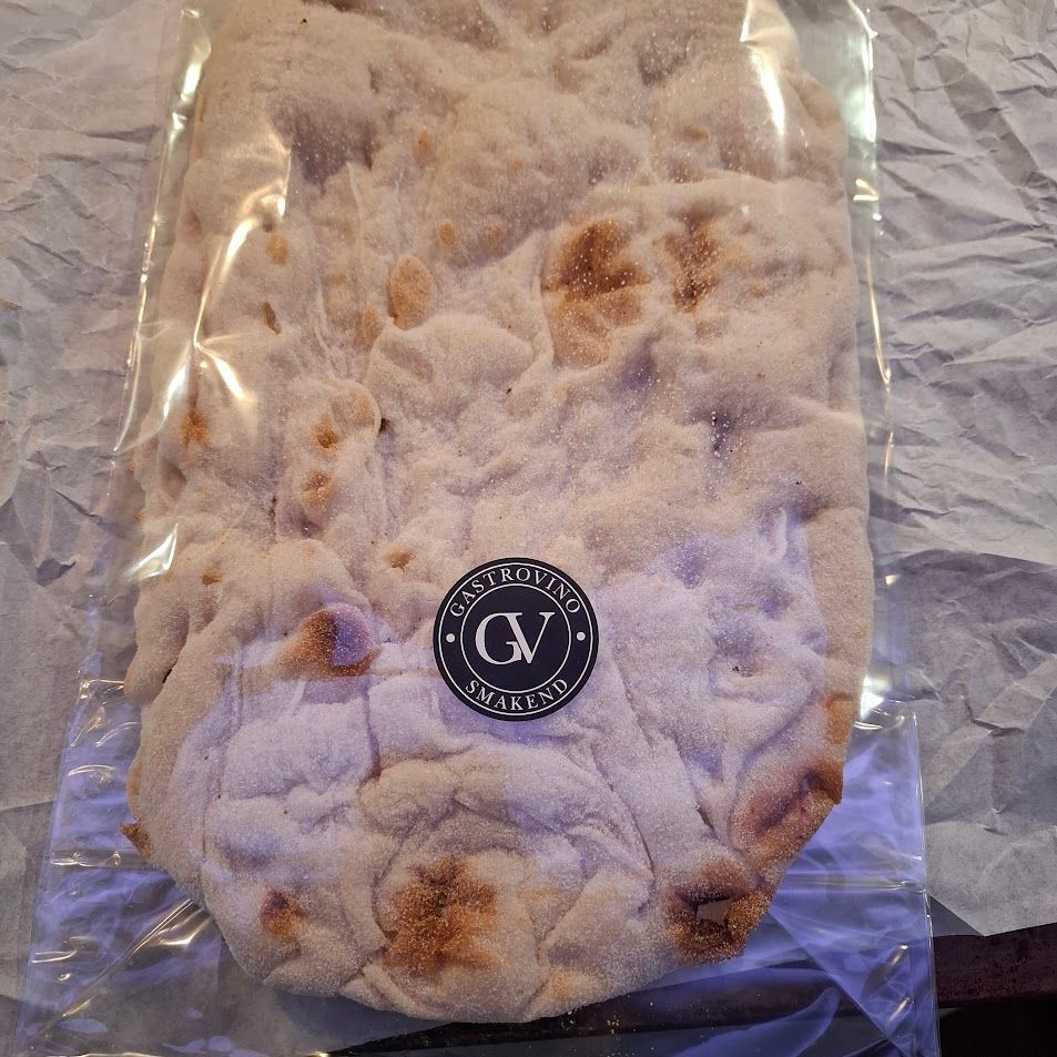 Platbrood in een doorzichtige plastic verpakking, voorzien van een zwart-wit ronde sticker.