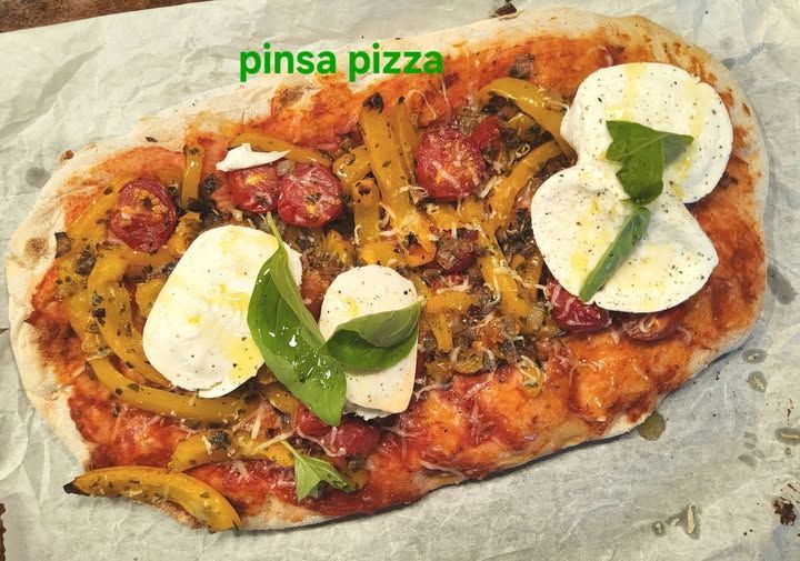 Verderop de pagina staat het recept Pinsa pizza met gele paprika, tomaten, mozzarella en basilicum op bakpapier.