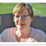Vrouw met bril lacht buiten.