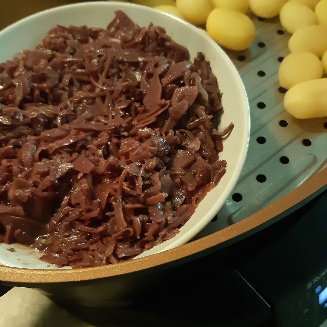 Een kom roodbruine gekookte kool naast een schaal met gele gekookte aardappelen.