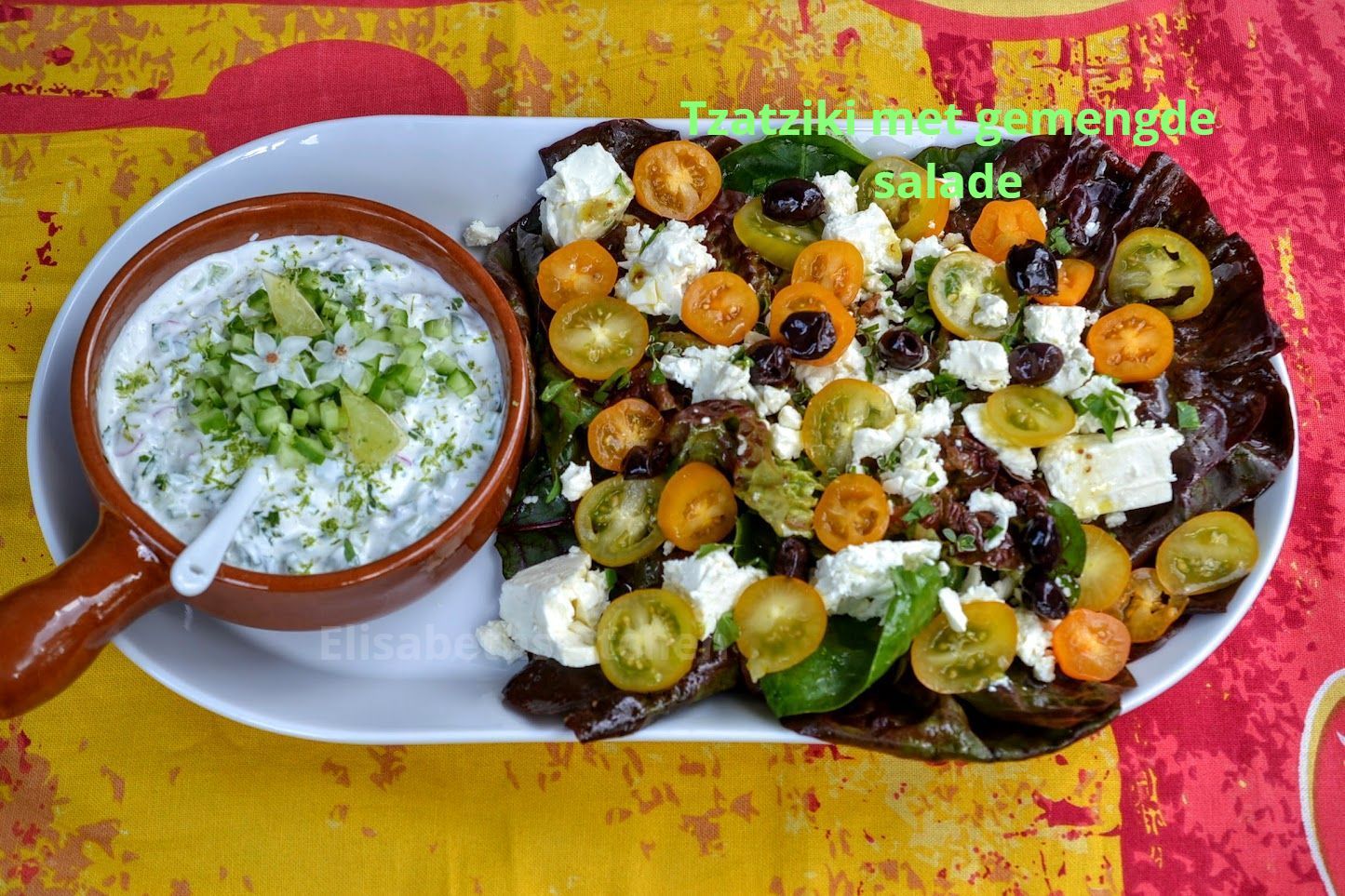 Tzatziki met salade. Wit bord met een kom tzatziki en salade met tomaten, olijven en feta.
