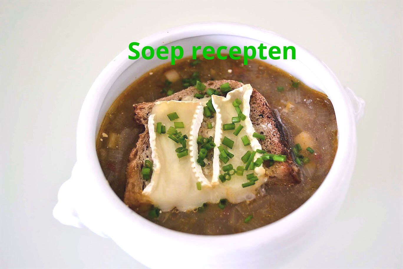 Soep in een witte kom, gegarneerd met brood, brie en bieslook. De tekst luidt: