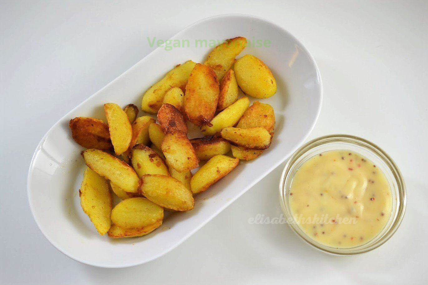 Geroosterde aardappelpartjes in een witte schaal met mosterdsaus.