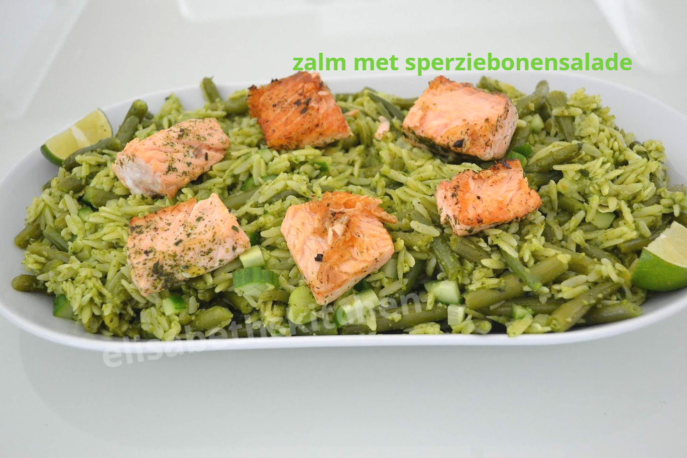 Zalm met sperziebonensalade op een wit bord. De zalmfilets liggen op een bedje van groene rijst en sperziebonen.