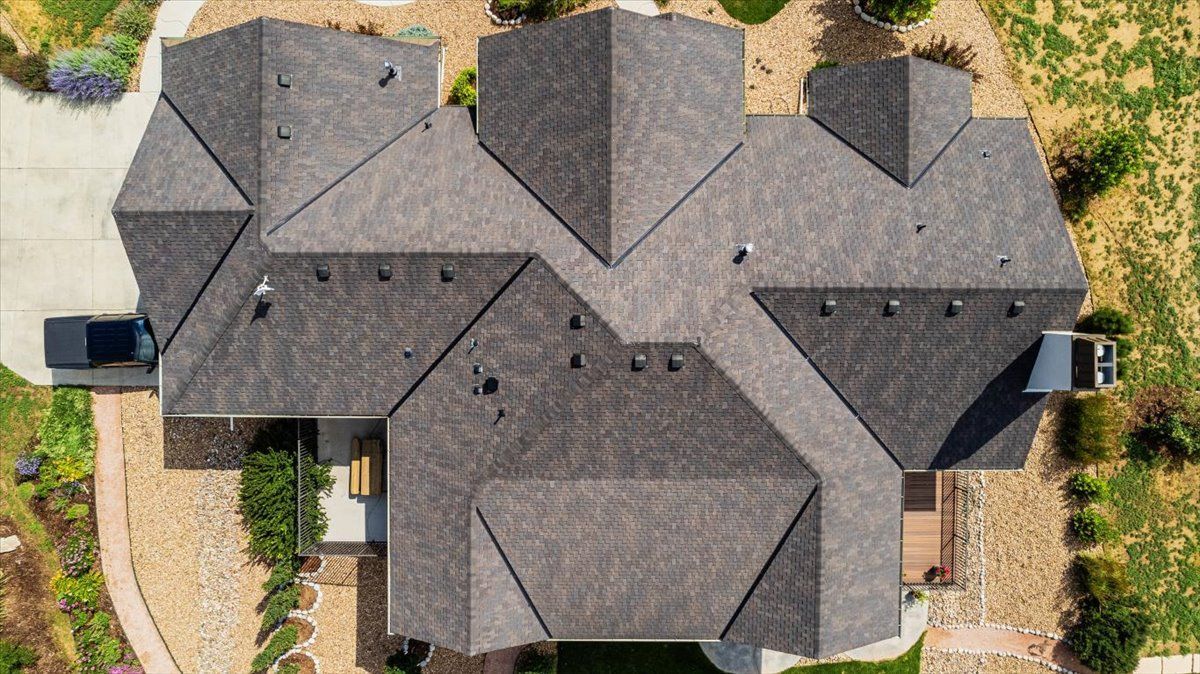 Aerial view of a house with a complex, dark gray roof.
