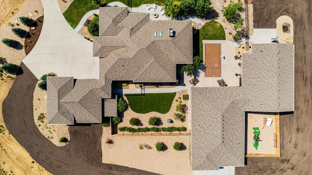 Aerial view of a large, multi-winged house with a driveway, yard, and swimming pool.