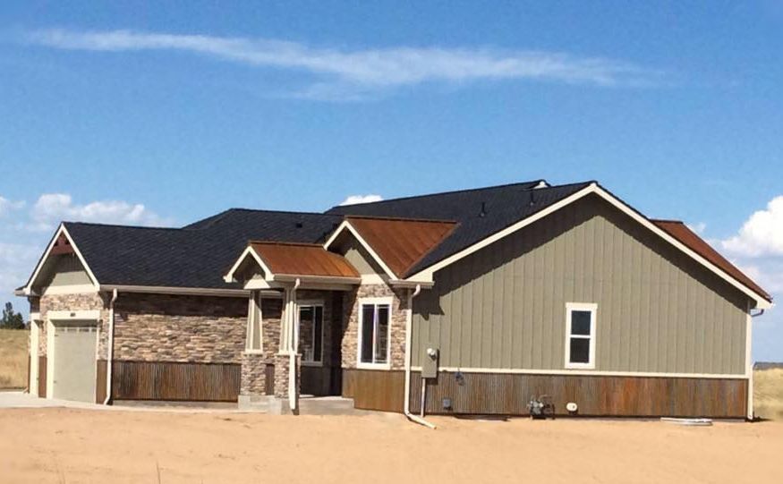 Ranch-style house with brown, tan, and gray siding and a blue sky background.