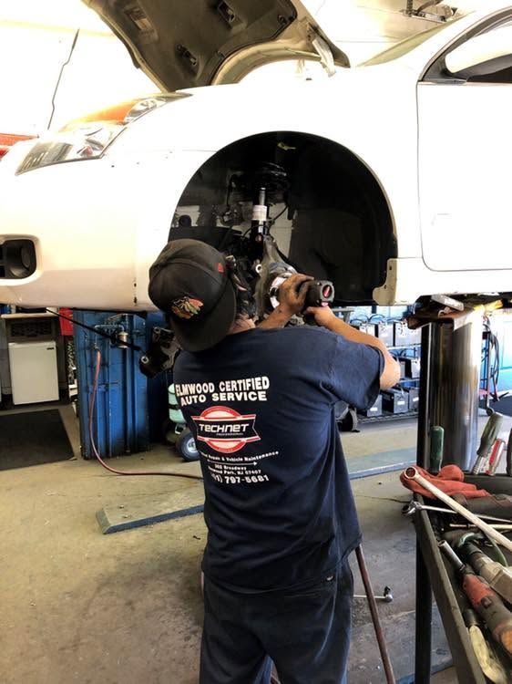 Technician Performing Front Suspension Service On A Lifted Vehicle | Elmwood Certified Powered by Ampro Auto
