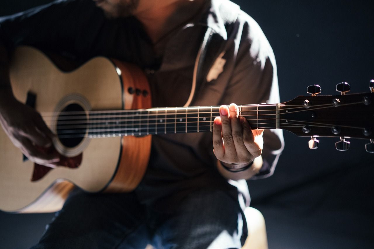 a man is playing an acoustic guitar in a dark room